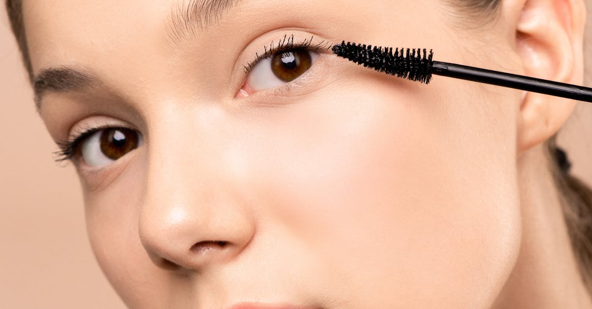Close-up of a young woman applying mascara to enhance her eyelashes.