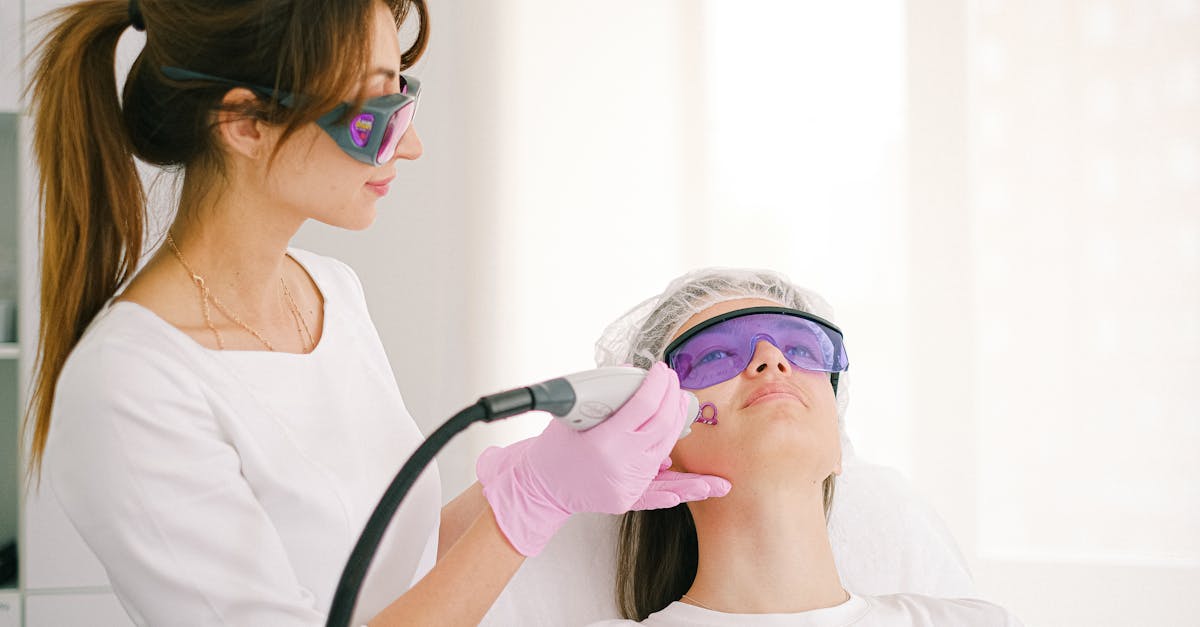 A cosmetologist performing laser treatment on a woman in a clinic setting.