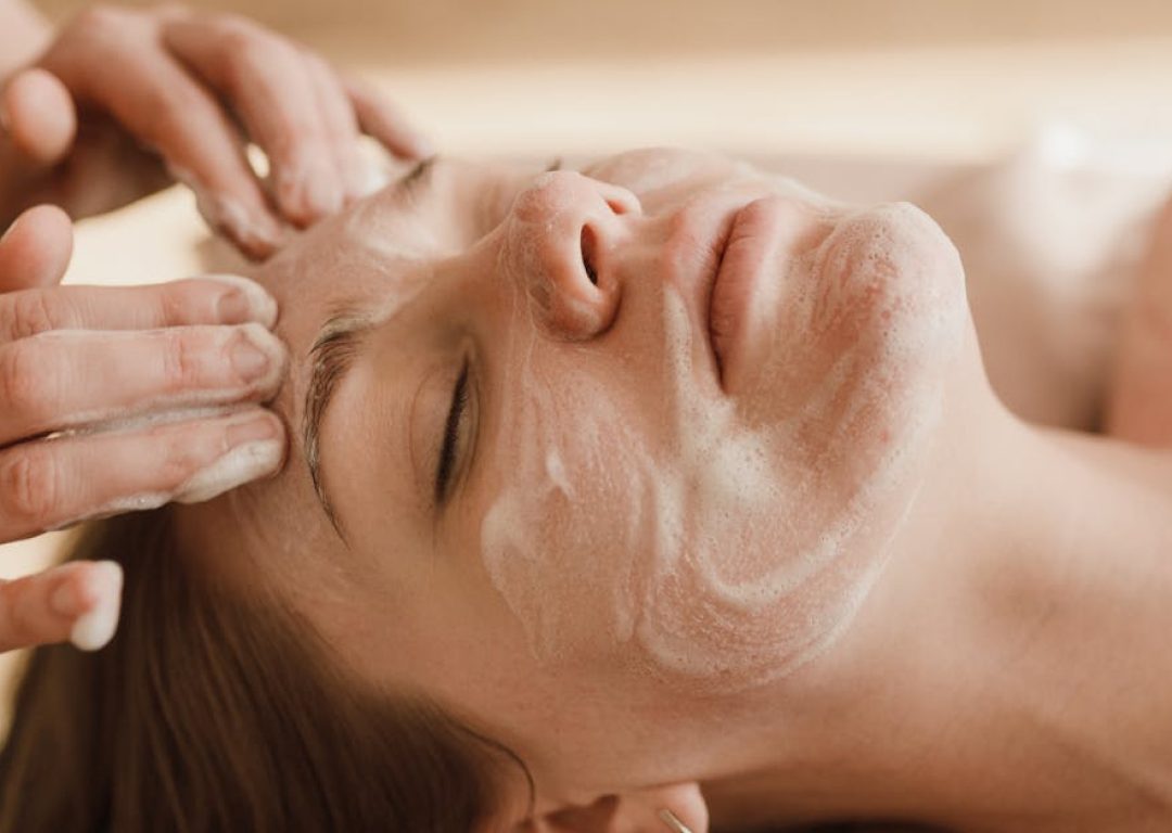 A close-up of a woman receiving a soothing facial massage with a skincare mask.